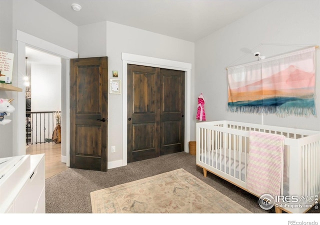 carpeted bedroom featuring a crib and baseboards