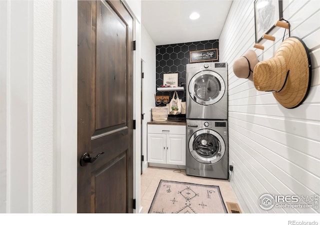 laundry area with stacked washing machine and dryer, cabinet space, light tile patterned floors, and recessed lighting