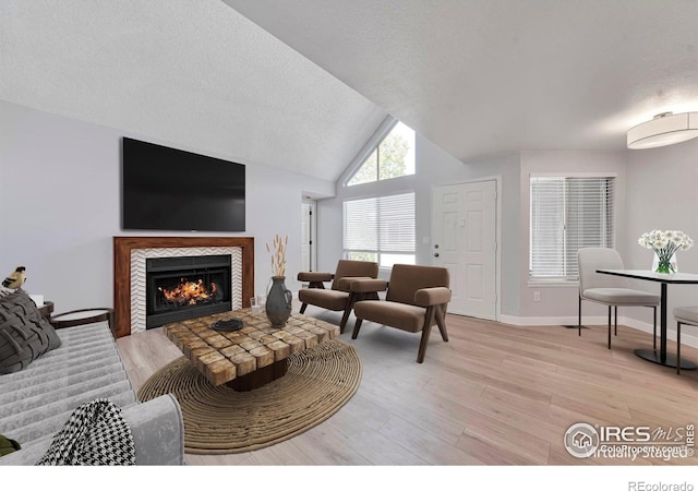12525 E Tennessee Cir Unit E, Aurora, CO 80012 - living room featuring a fireplace, a textured ceiling, light wood-style floors, lofted ceiling, and baseboards