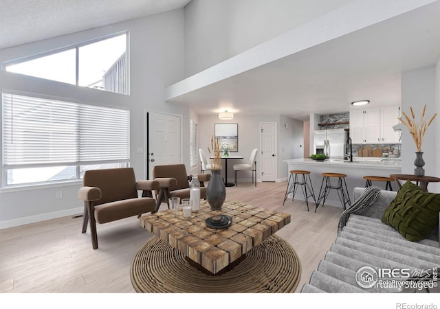 12525 E Tennessee Cir Unit E, Aurora, CO 80012 - living area featuring baseboards, light wood-style floors, and a high ceiling