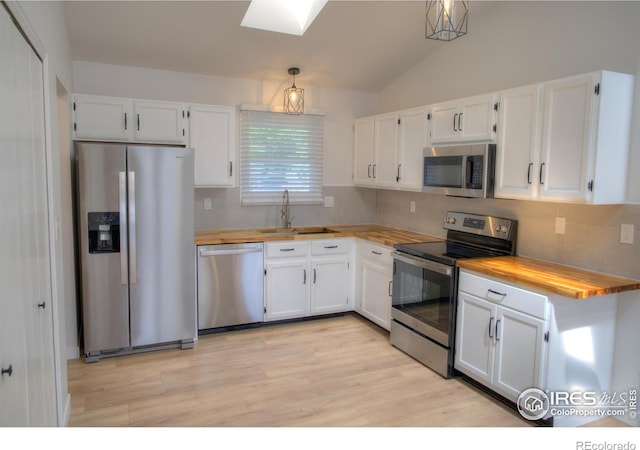 kitchen with stainless steel appliances, a sink, white cabinets, lofted ceiling, and light wood-style flooring