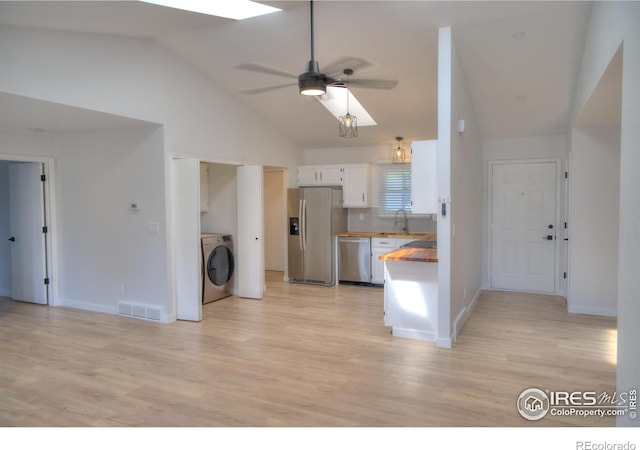 kitchen featuring stainless steel appliances, a sink, a ceiling fan, white cabinets, and light wood-type flooring