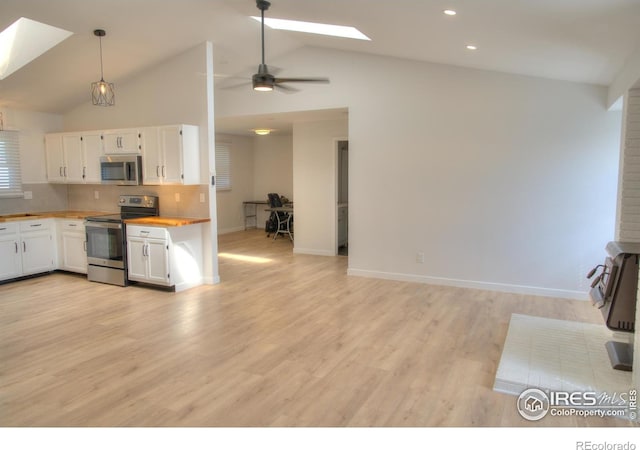 kitchen featuring appliances with stainless steel finishes, a skylight, wood counters, white cabinets, and lofted ceiling