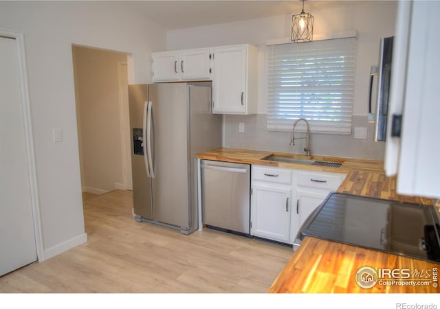 kitchen featuring stainless steel appliances, wood counters, a sink, and white cabinets