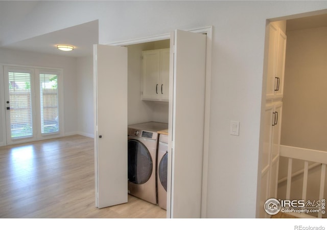 clothes washing area with cabinet space, light wood-style floors, washing machine and dryer, and baseboards