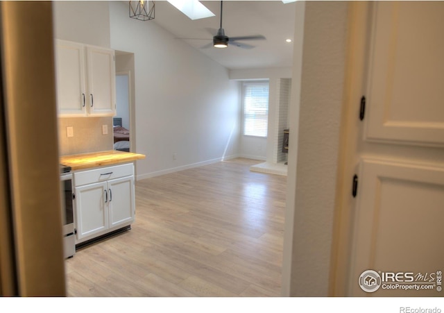 kitchen featuring vaulted ceiling, a ceiling fan, white cabinetry, electric range oven, and light wood finished floors