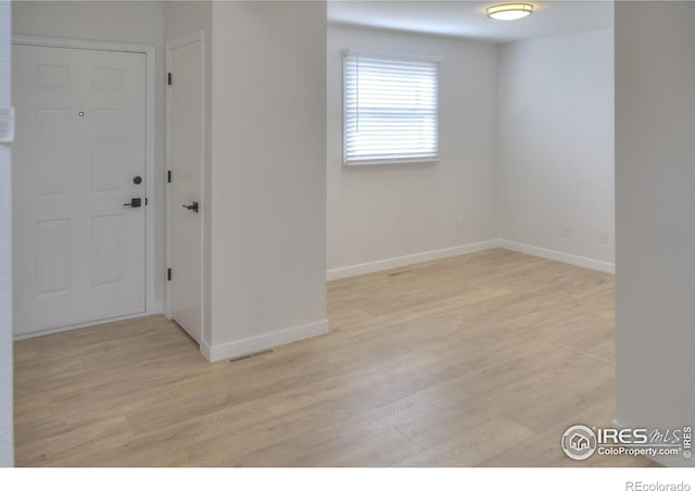 empty room featuring light wood finished floors and baseboards
