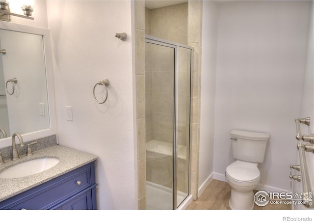 full bath with a stall shower, toilet, wood finished floors, and vanity