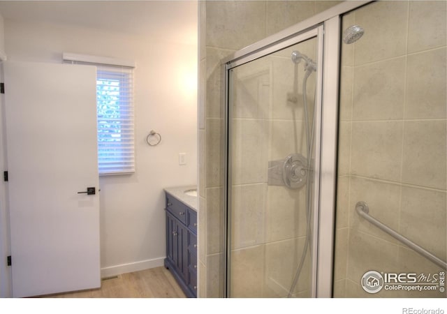 bathroom with a shower stall, wood finished floors, vanity, and baseboards