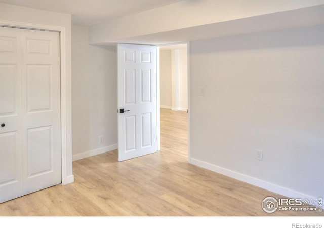 unfurnished bedroom featuring baseboards, light wood-style floors, and a closet