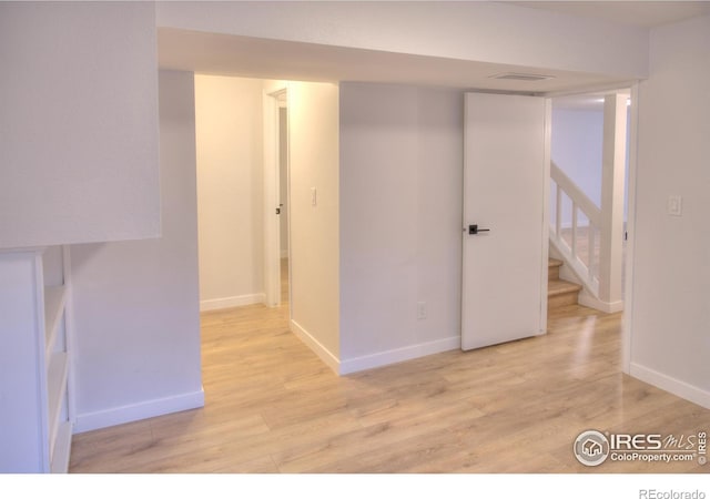 finished below grade area featuring light wood-style floors, stairway, and baseboards