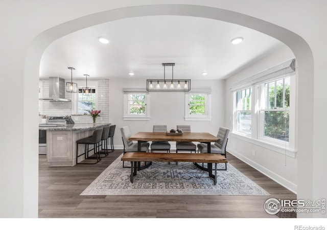 dining area with arched walkways, dark wood-type flooring, baseboards, and recessed lighting