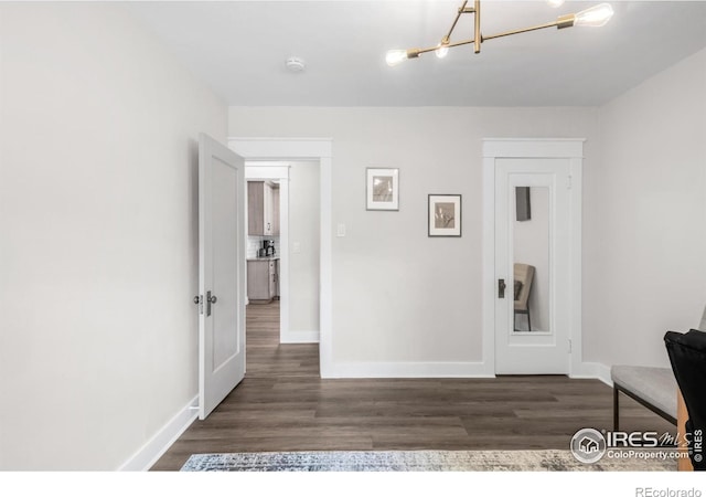 hallway with baseboards, a chandelier, and dark wood-type flooring