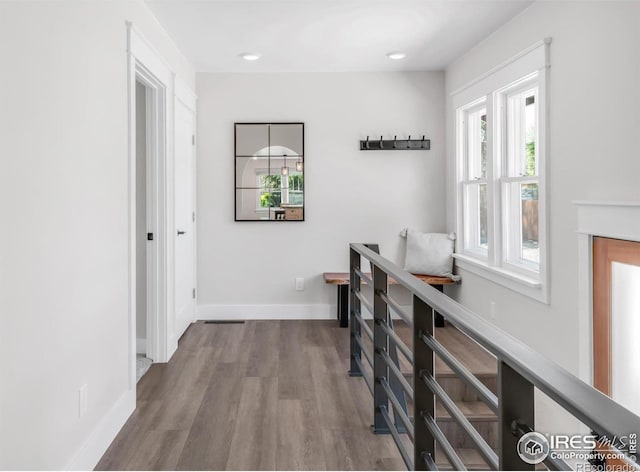 hall featuring healthy amount of natural light, wood finished floors, baseboards, and recessed lighting