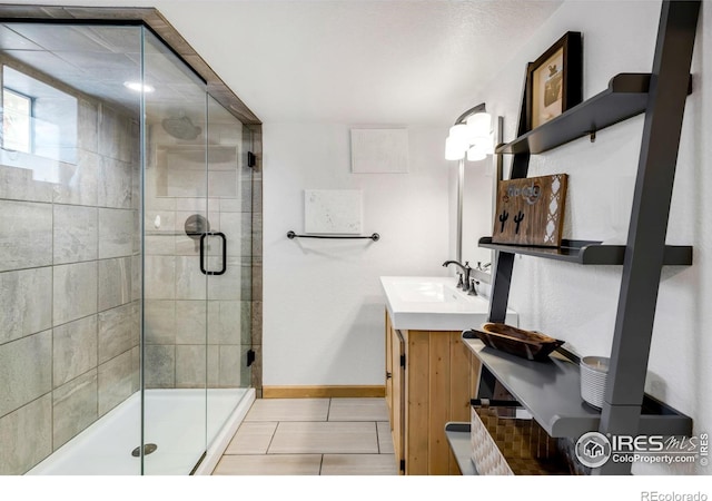 full bathroom featuring a stall shower, tile patterned flooring, baseboards, and vanity