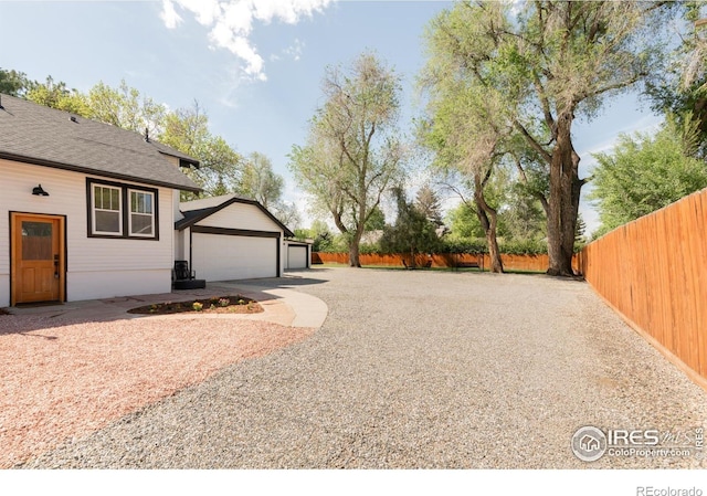 view of yard featuring fence, concrete driveway, and a detached garage