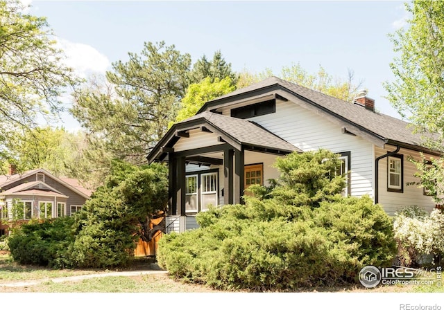 view of front of property featuring a chimney and a shingled roof