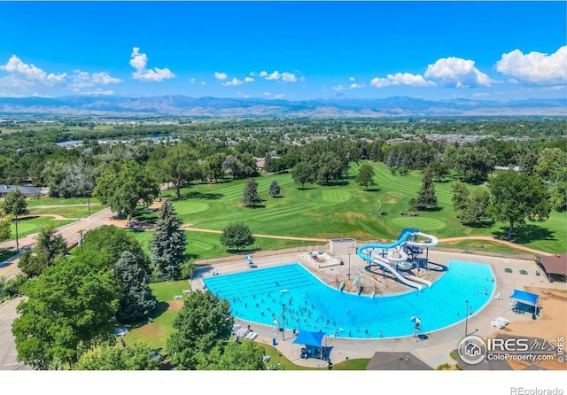 aerial view of a mountain backdrop, a pool area, a golf club, and a tree filled landscape