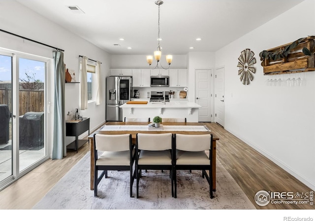 dining space featuring light wood finished floors, recessed lighting, baseboards, and a chandelier