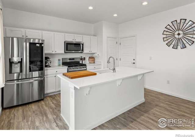 kitchen with stainless steel appliances, a sink, light wood-type flooring, light countertops, and recessed lighting