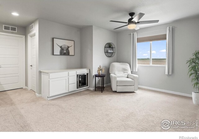 living area with light colored carpet, baseboards, and ceiling fan
