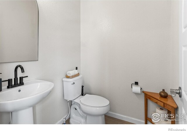 bathroom featuring a sink, baseboards, toilet, and wood finished floors