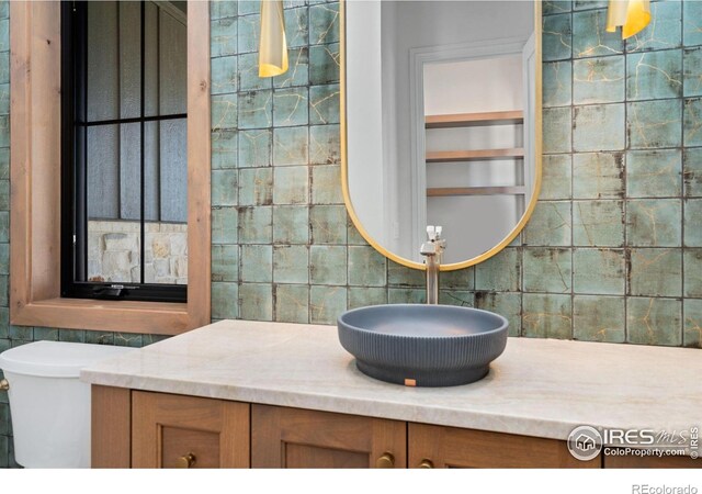 951 Warbling Dr, Windsor, CO 80550 - half bath featuring decorative backsplash, vanity, toilet, and tile walls