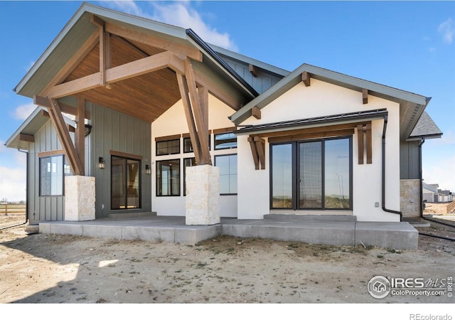 951 Warbling Dr, Windsor, CO 80550 - rear view of house featuring stone siding, board and batten siding, and stucco siding