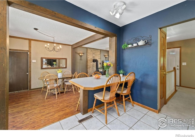 5930 Mars Dr, Fort Collins, CO 80525 - dining area featuring a wood stove, a chandelier, baseboards, light wood-type flooring, and a textured ceiling