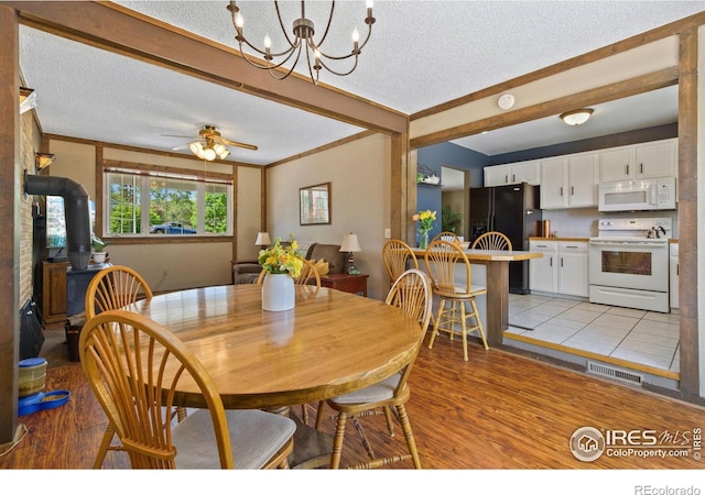 5930 Mars Dr, Fort Collins, CO 80525 - dining space with a wood stove, a textured ceiling, light wood-type flooring, a chandelier, and beamed ceiling