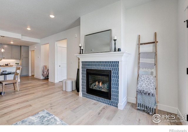 living area with light wood-style flooring, baseboards, a fireplace, and recessed lighting