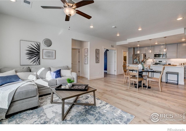 living area with ceiling fan, light wood-style flooring, baseboards, and recessed lighting