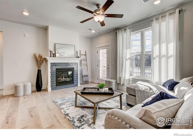living area featuring ceiling fan, wood finished floors, a tile fireplace, baseboards, and recessed lighting