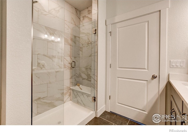 bathroom featuring a marble finish shower and a textured wall