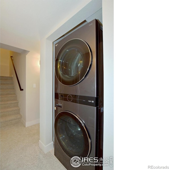 laundry room with stacked washer / dryer, carpet flooring, and baseboards