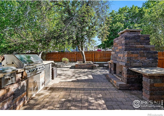 1970 Hamron Ct, Erie, CO 80516 - view of patio with exterior fireplace, a grill, a fenced backyard, and exterior kitchen