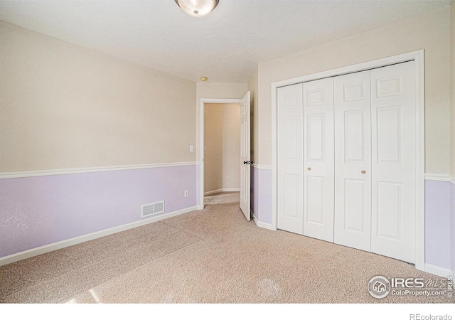 unfurnished bedroom with carpet floors, a closet, and baseboards