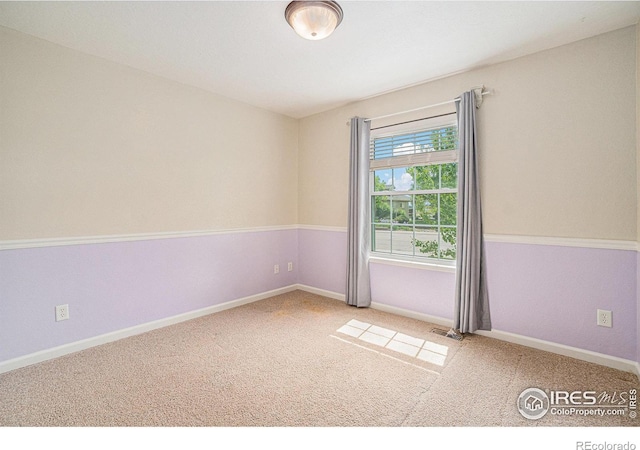 carpeted spare room featuring baseboards