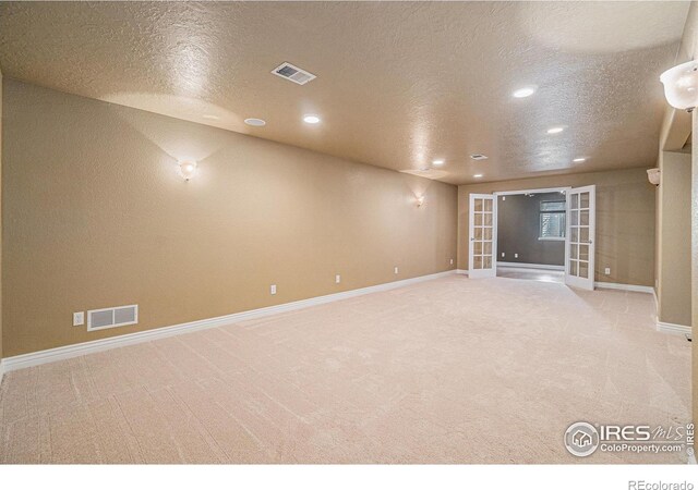 carpeted empty room with french doors, recessed lighting, baseboards, and a textured ceiling