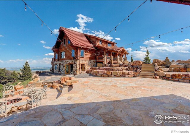 9126 Gold Mine Rd, Loveland, CO 80538 - rear view of house with stone siding, a patio area, metal roof, and log exterior