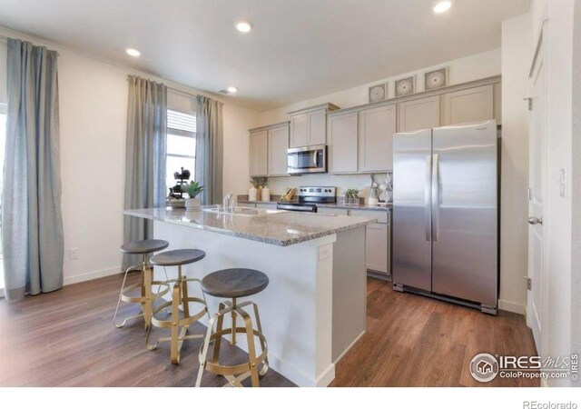 4204 Sandstone Dr, Mead, CO 80504 - kitchen featuring appliances with stainless steel finishes, gray cabinets, dark wood-style flooring, an island with sink, and recessed lighting