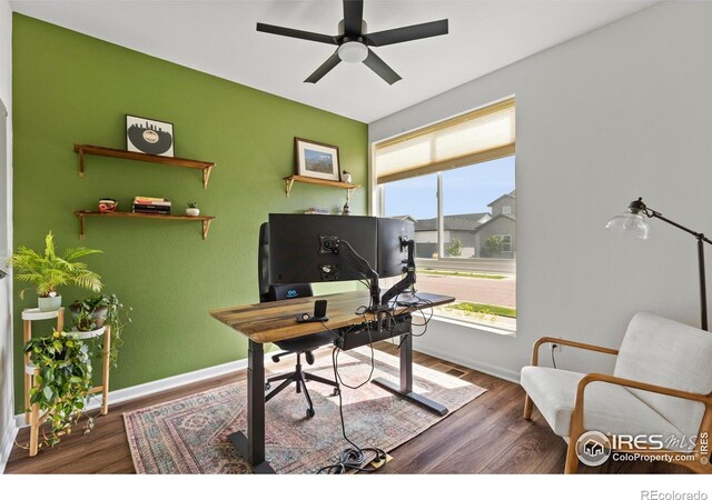 office space featuring a ceiling fan, baseboards, and wood finished floors