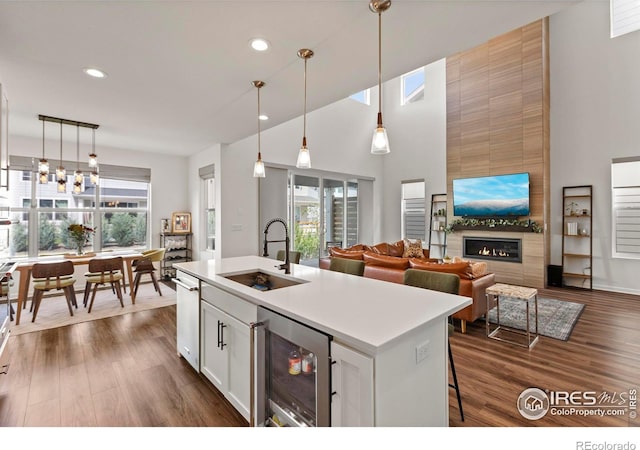 kitchen featuring a sink, wine cooler, open floor plan, an island with sink, and a fireplace