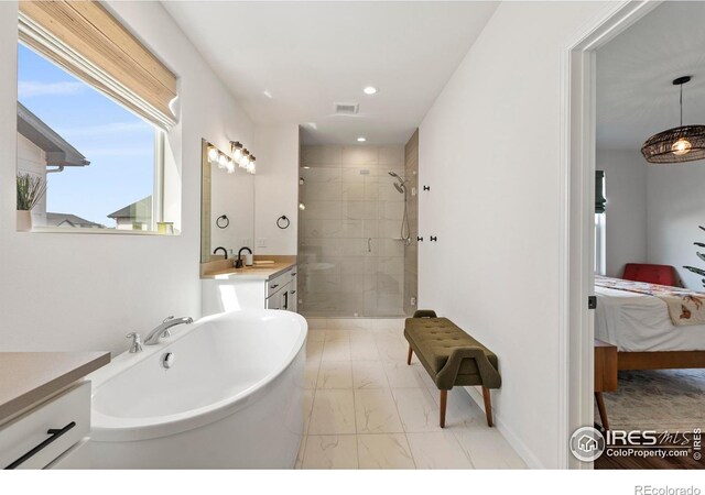 ensuite bathroom with marble finish flooring, a shower stall, a freestanding tub, recessed lighting, and vanity
