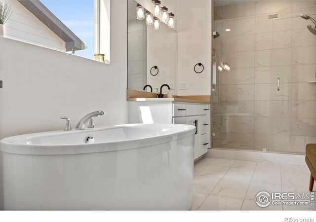 full bath with marble look tiles, a stall shower, a freestanding tub, and vanity