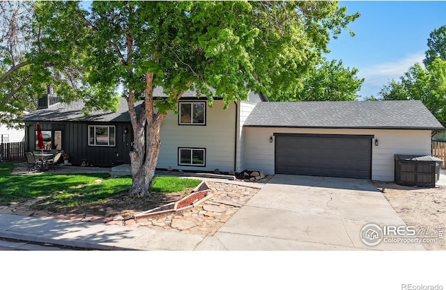 view of front of property with a garage, concrete driveway, roof with shingles, and fence