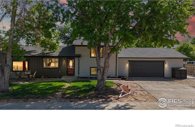 split level home featuring an attached garage, concrete driveway, and roof with shingles