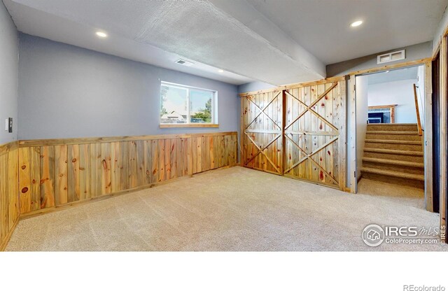 spare room with wood walls, carpet flooring, wainscoting, recessed lighting, and stairs