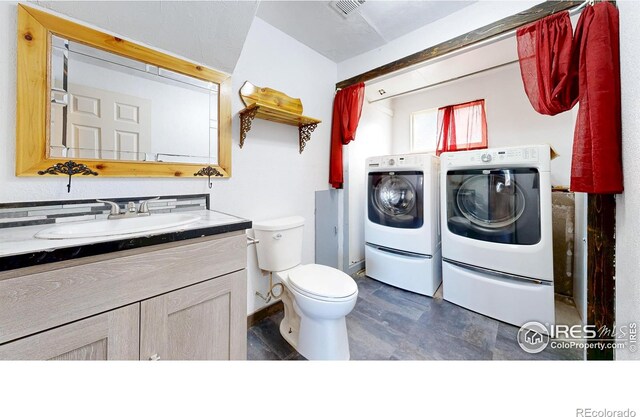 bathroom with washing machine and clothes dryer, toilet, and vanity