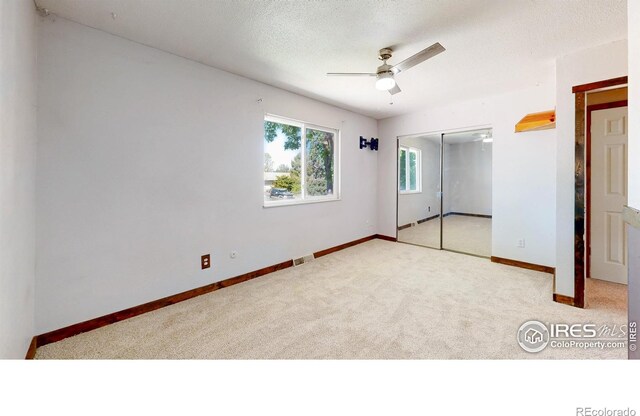 unfurnished bedroom with carpet, a closet, baseboards, a ceiling fan, and a textured ceiling